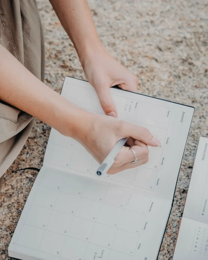 Frau macht sich Notizen in ein aufgeschlagenes Notizbuch – Symbol für individuelles Finanztraining im 1:1.