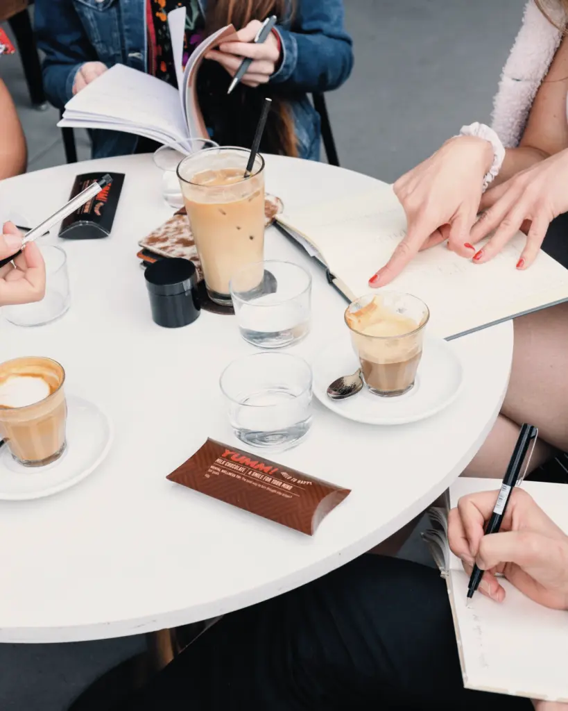 Workshop-Tisch mit Kaffee und Notizzetteln, auf denen Frauen während des Finanzseminars schreiben.